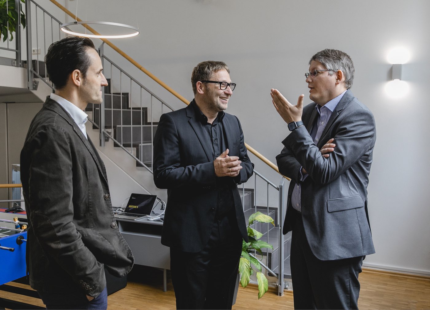 Drei Personen im Gespräch an der Treppe von Loft 18