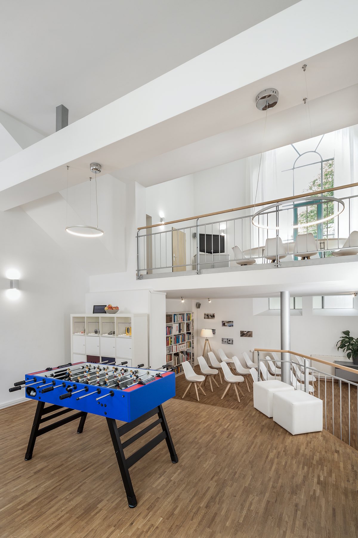 Doppelhöhiger Innenraum von Loft 18 mit Empore, Treppe, Bücherregal und Kickertisch