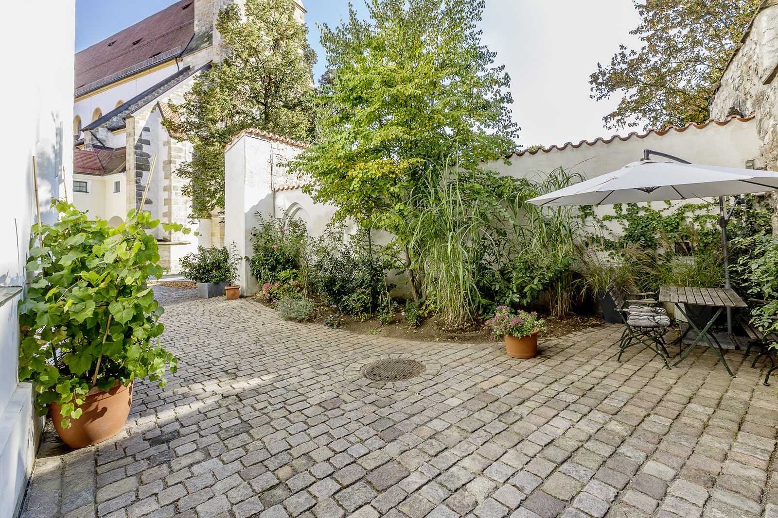 Begrünter Innenhof von Loft 18 mit Sitzplatz unter dem Sonnenschirm