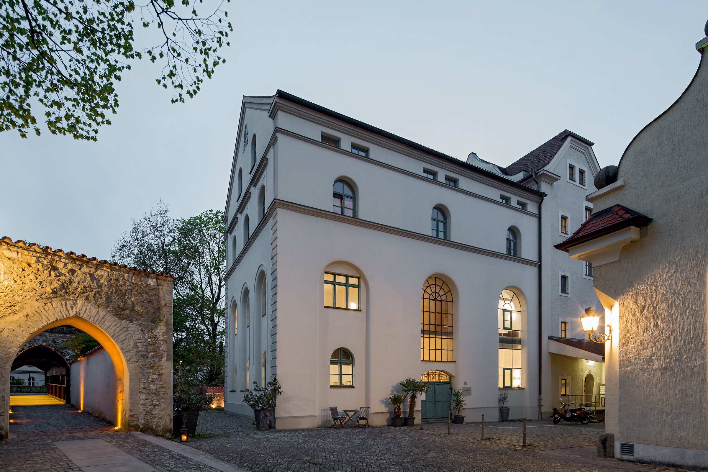 Loft 18 in Amberg bei Dämmerung, beleuchtete Fassade der denkmalgeschützten ehemaligen Brauerei am Malteserplatz